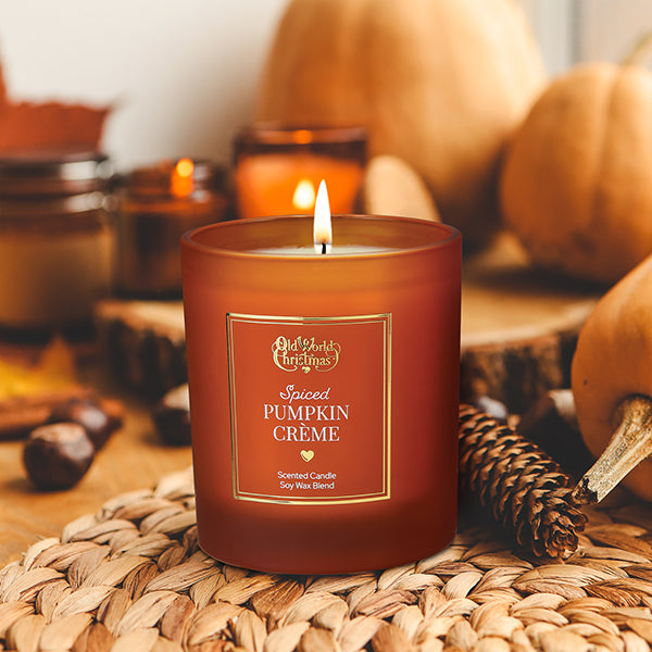 an orange candle sits on an autumnal 
