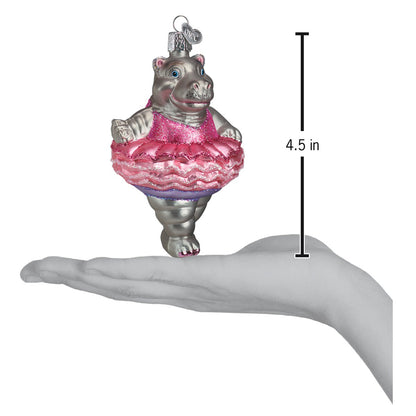 Decorative hippo ornament in a pink dress held in a hand with a measurement label.