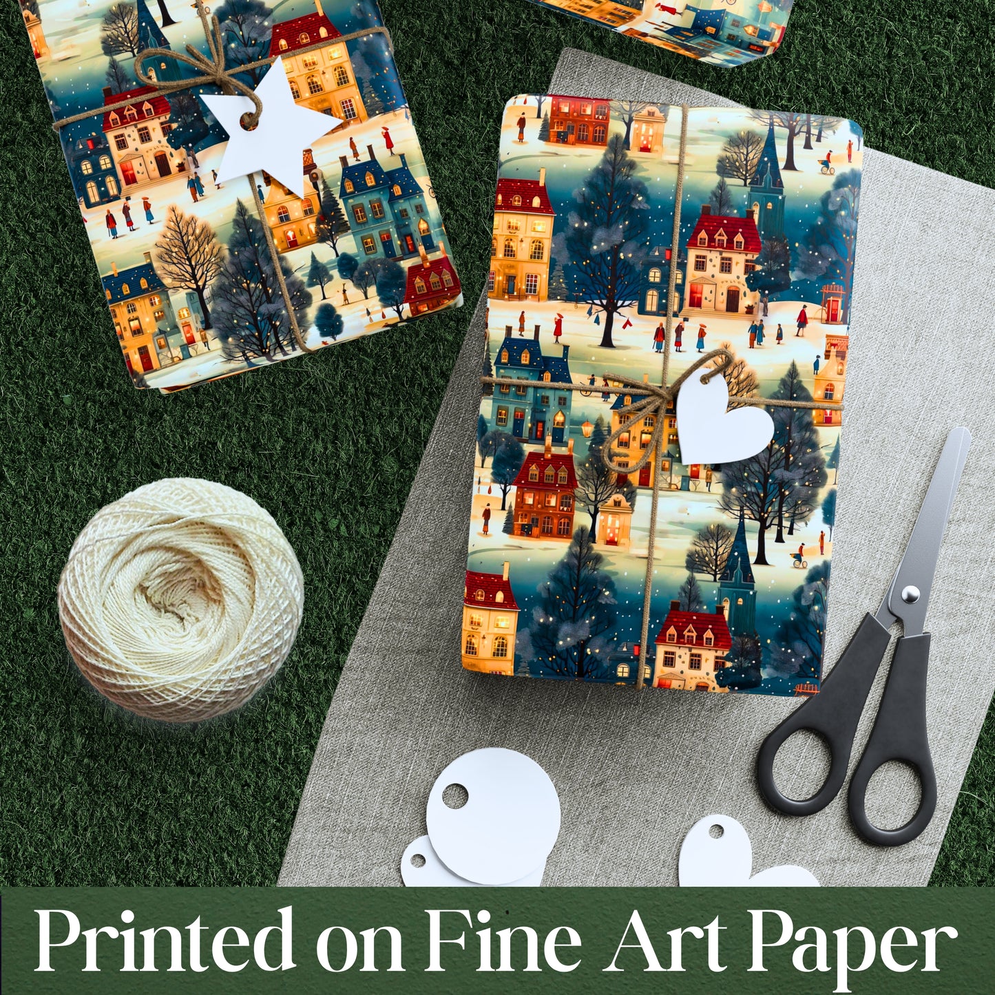 Two packages of decorative paper with a winter village design, a ball of yarn, and scissors on a textured surface.