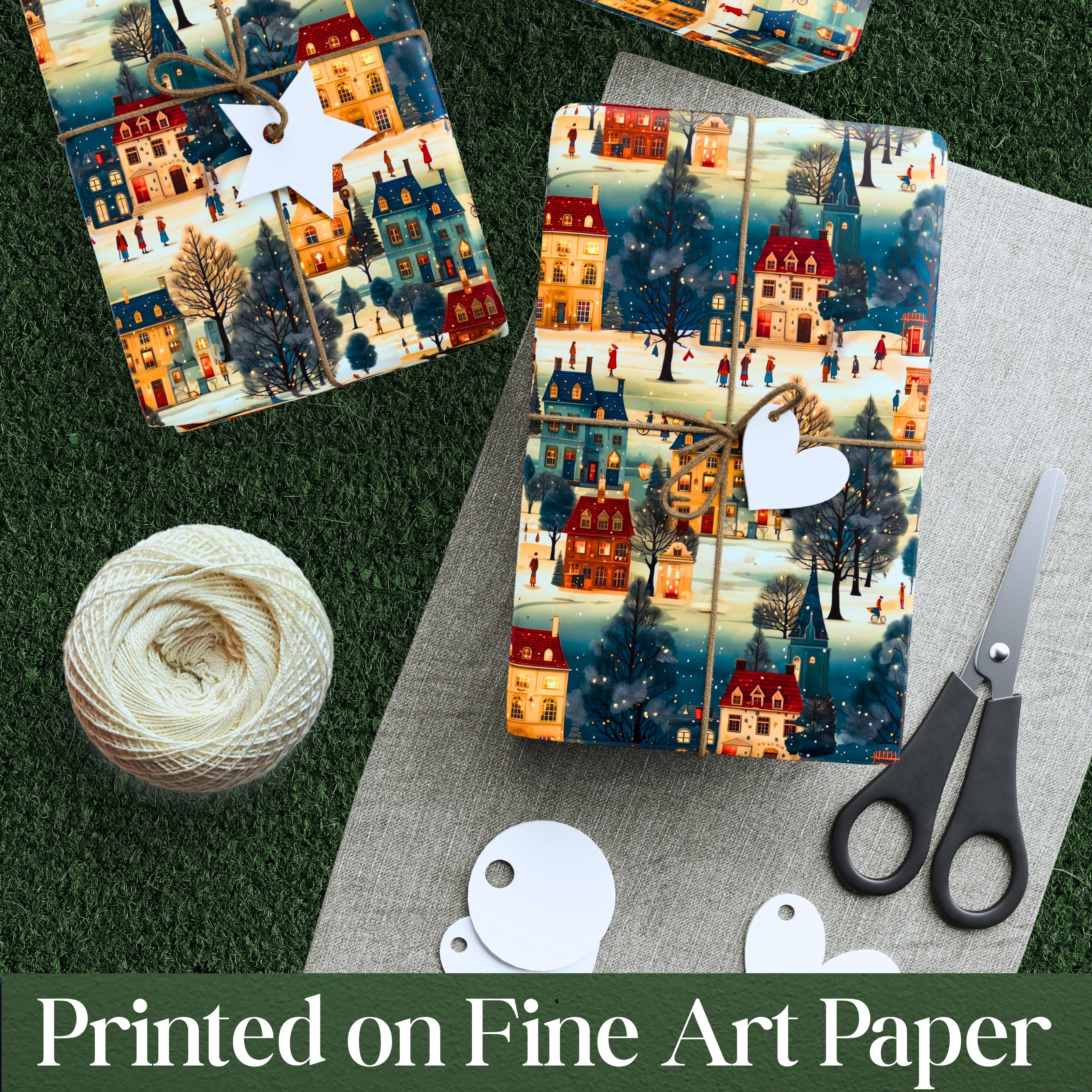 Two packages of decorative paper with a winter village design, a ball of yarn, and scissors on a textured surface.