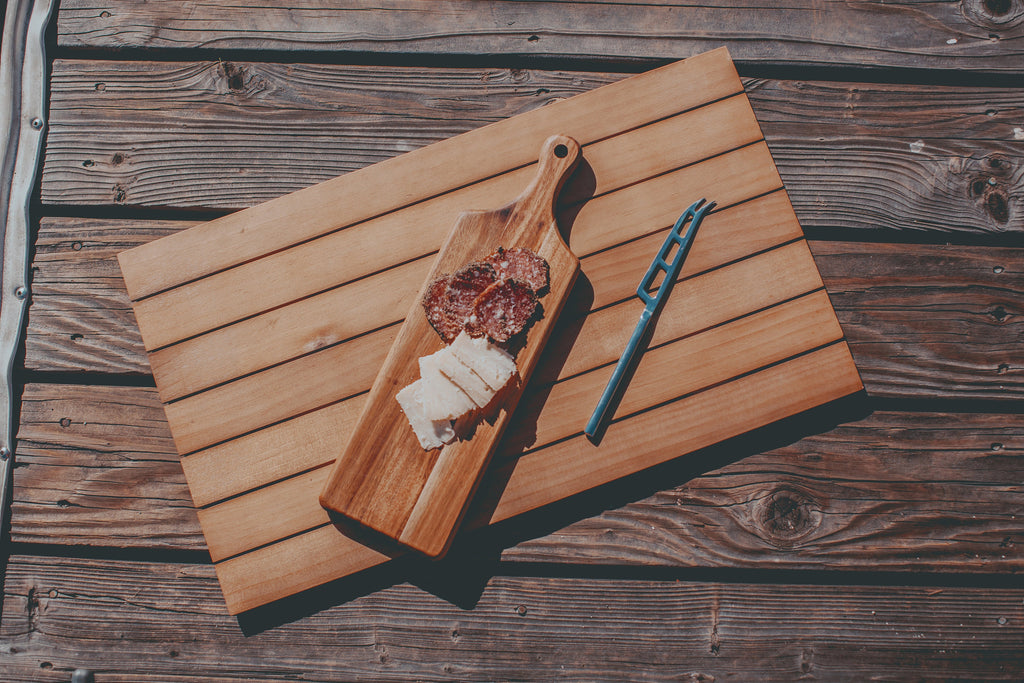 Wooden cutting board with sliced meat and bread on a wooden surface