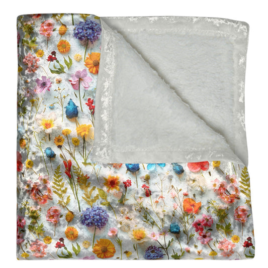 Floral patterned blanket with a gray reverse side on a white background