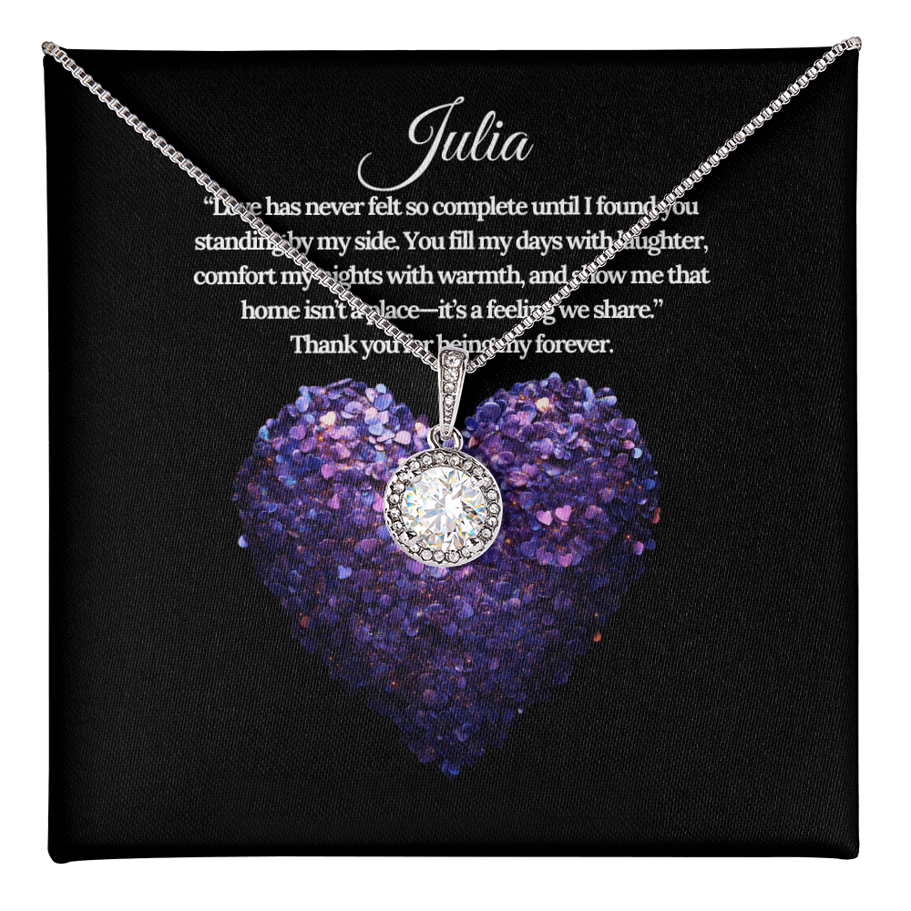 a beautiful crystal pendant surrounded by smaller round crystals hangs freely from a white gold box chain necklace is elegantly displayed on a purple heart background with a romantic grateful quote in white text written to Julia.